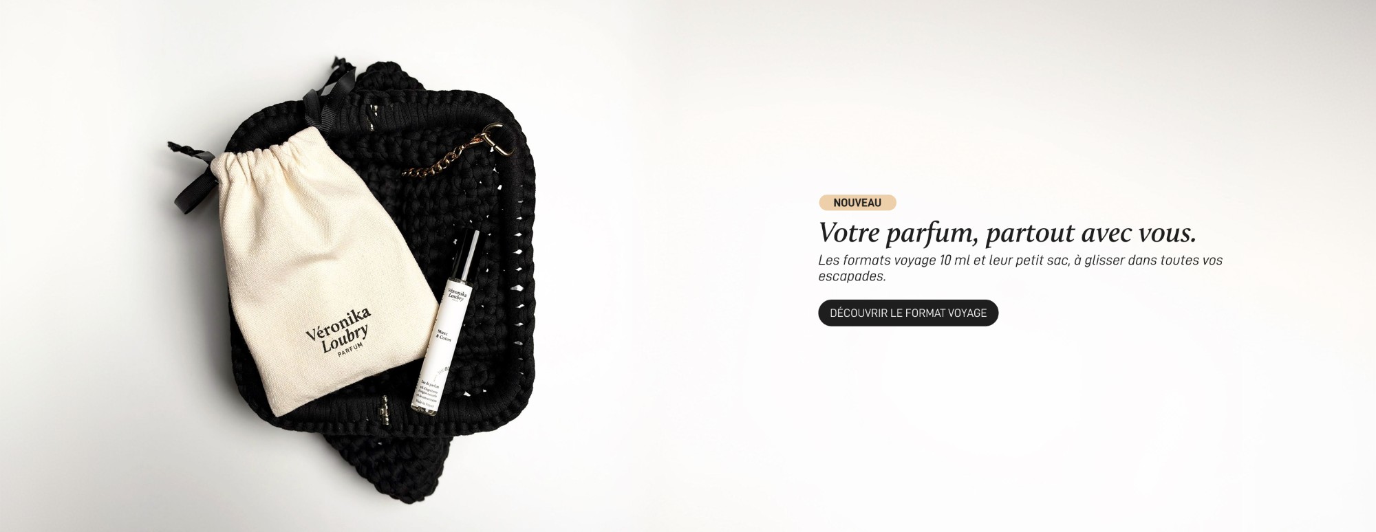 Format voyage 10 ml Véronika Loubry Parfum, le flacon et sa pochette en coton posés sur un sac